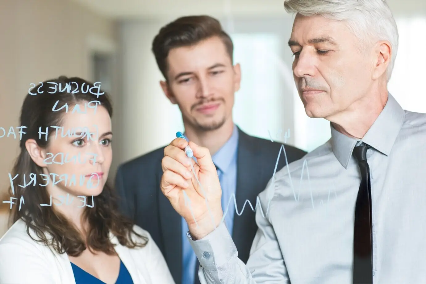 Führungskraft zeichnet ein Diagramm und coacht Kolleginnen und Kollegen.