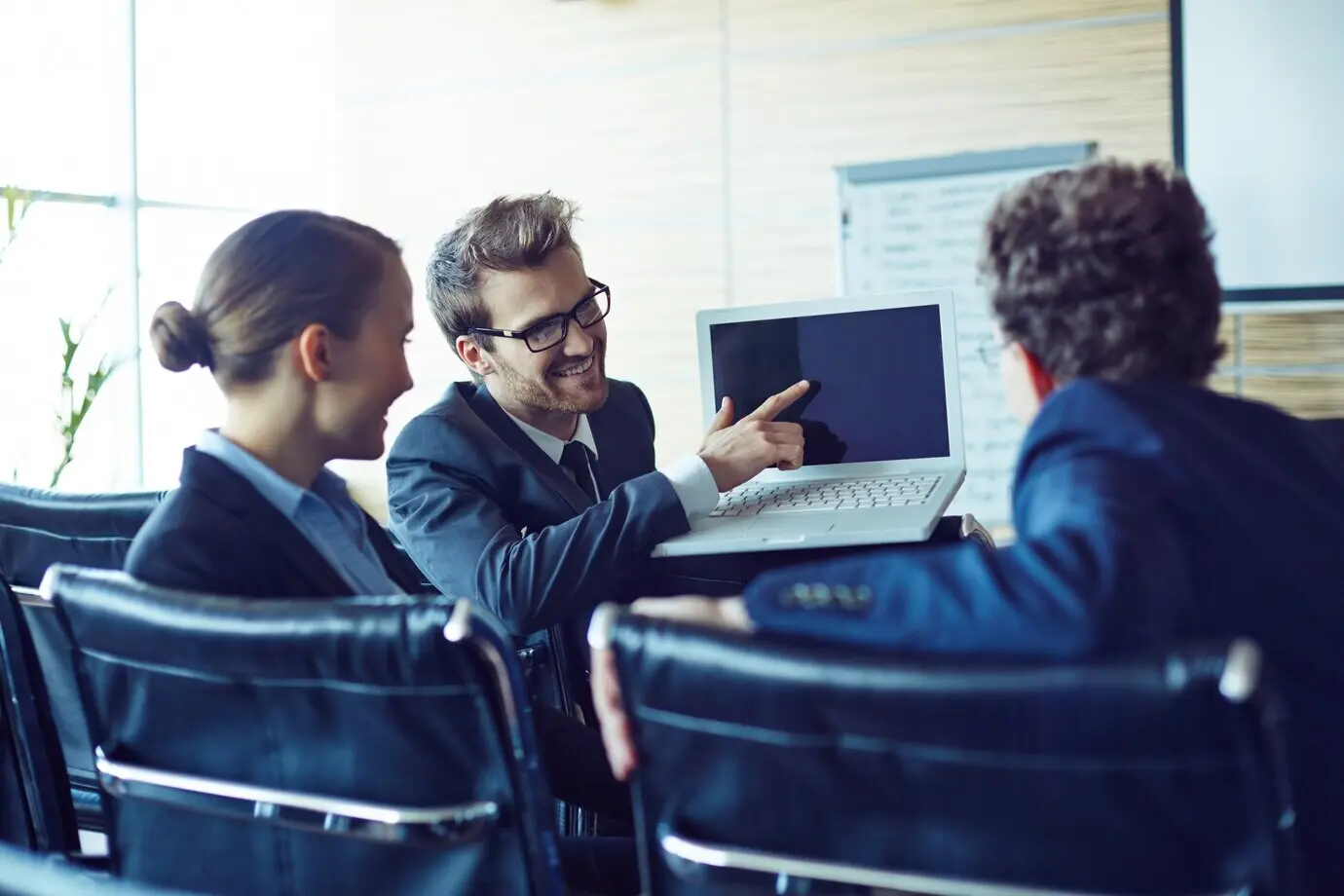 Junge Führungskraft hält einen Laptop und zeigt darauf